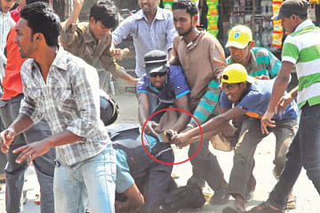 Islami Chhatra Shibir men try to get firearm chained to the waist of a policeman during an attack on law enforcers at Shalbagan in Rajshahi city. Photo: Star/Focus Bangla