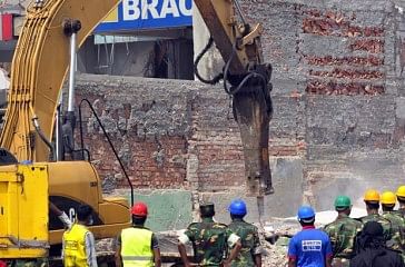 This Monday photo shows rescuers using a crane to remove heavy concrete slabs of the collapsed building at Savar. Photo: STAR