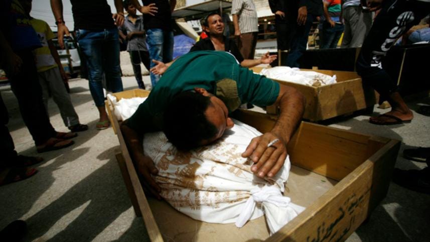 Iraqi men mourn over bodies after they lost five members of their family in a suicide bombing that ripped through Baghdad's busy shopping district of Karrada