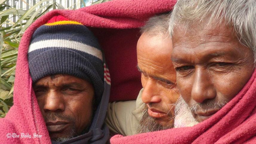 Wrapping a blanket around them, three men huddle together