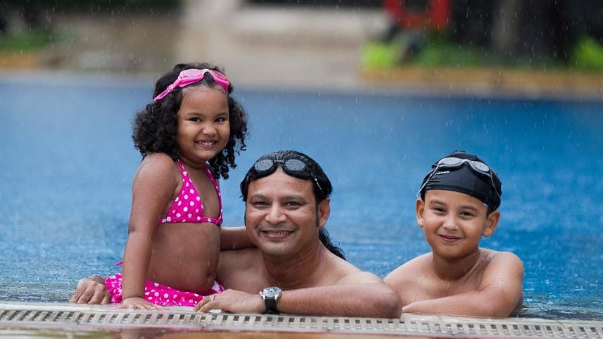 Father and children enjoying leisure hours in the pool
