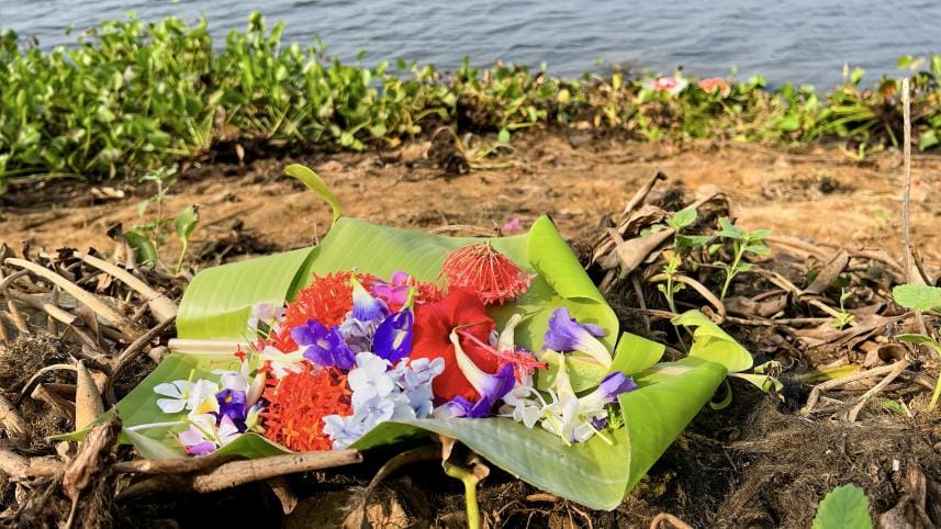 Flowers being offered to the river on the day of Ful Biju