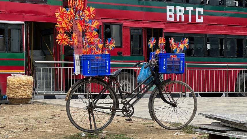 A cycle on a sidewalk being used as a makeshift street side store selling paper fans.   