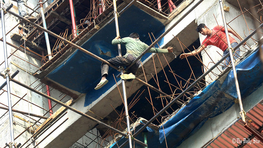 Without any safety gear, two labourers work at an under-construction high rise Without any safety gear, two labourers work at an under-construction high rise