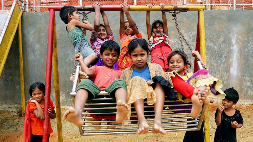 Rohingya refugee children play on a swing at a refugee camp in Cox's Bazar Rohingya refugee children play on a swing at a refugee camp in Cox's Bazar