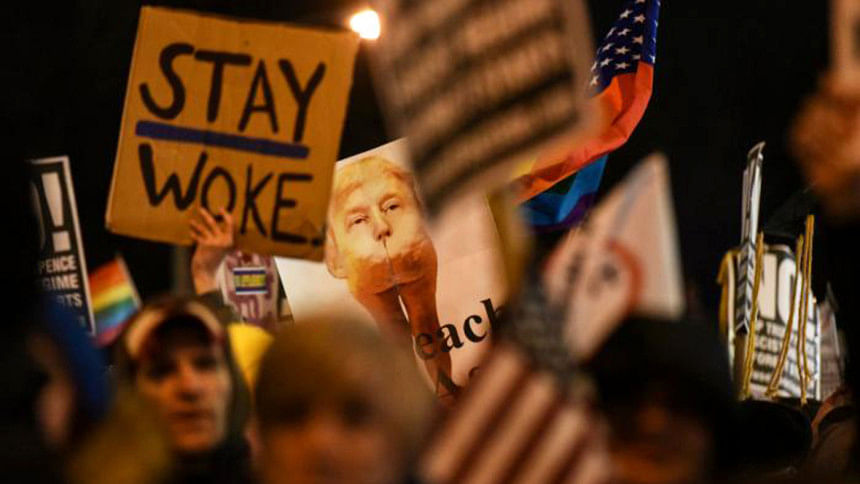 People hold signs at a protest against US President-elect Donald Trump People hold signs at a protest against US President-elect Donald Trump
