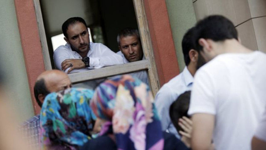 Forensic Medical Centre officials look out on family members who had gathered to hear news. Forensic Medical Centre officials look out on family members who had gathered to hear news.