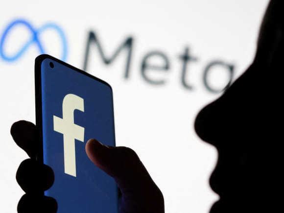 Woman holds smartphone with Facebook logo in front of a displayed logo for Meta in this illustration picture taken October 28, 2021. Photo: Reuters