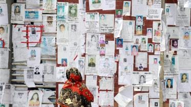 A woman looks at a wall filled with portraits of missing people on May 3, 2013 near the collapsed Rana Plaza building. PHOTO Ashraful Alam Tito Associated Press.jpg