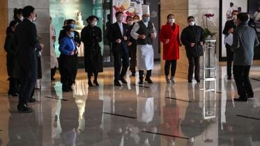 Hotel workers wearing protective masks exercise in the lobby 