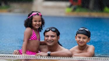 Father and children enjoying leisure hours in the pool