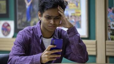 A photo of a man looking stressfully at his phone screen.
