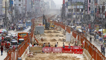 People crossing the street through the construction site of the metro railway.