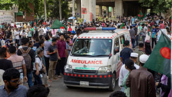 An ambulance driving through a narrow space accommodated by the crowd of protestors