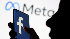 Woman holds smartphone with Facebook logo in front of a displayed logo for Meta in this illustration picture taken October 28, 2021. Photo: Reuters
