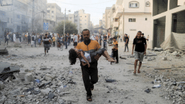 A Palestinian man carries a wounded girl at the site of Israeli strikes.png