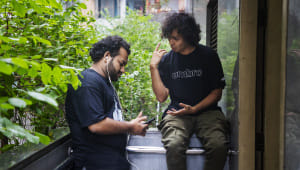 Two friends in one frame, one is talking and the other is listening to music