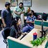 Female employee working diligently while her male counterparts loiter around.
