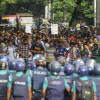 An army of police standing in the way of students protesting.