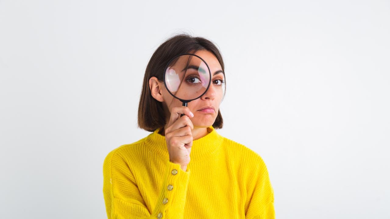 pretty-woman-yellow-sweater-white-held-magnifier-happy-positive-playful.jpg