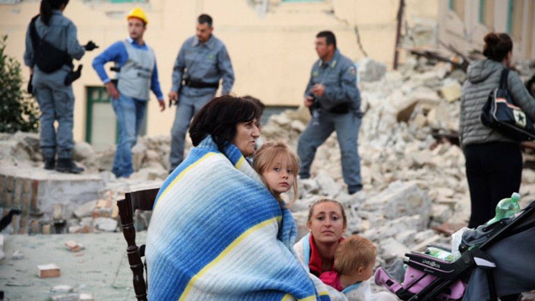 Victims sit among rubble of a house Italy, earthquake, disaster, Amatrice, rubble,
