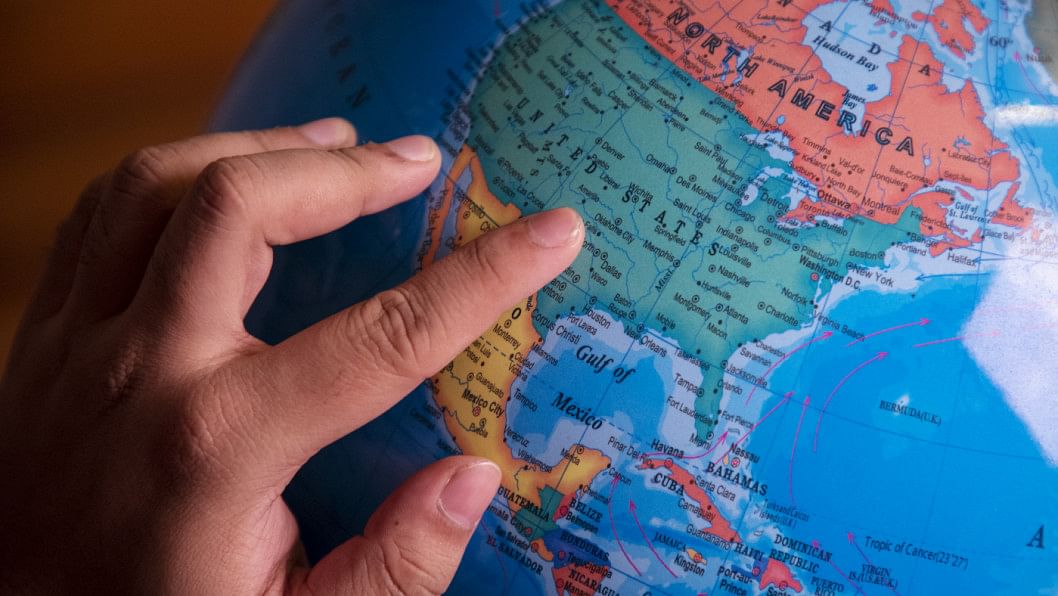 A person with their finger placed on a globe.