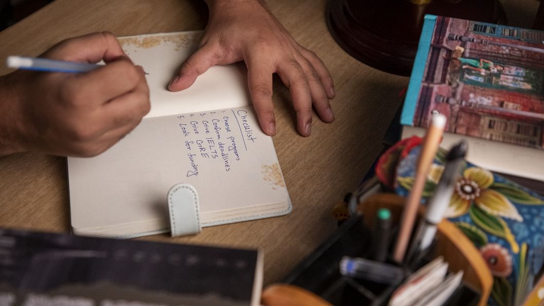 Person writing down their to-do list for applying for a masters degree.