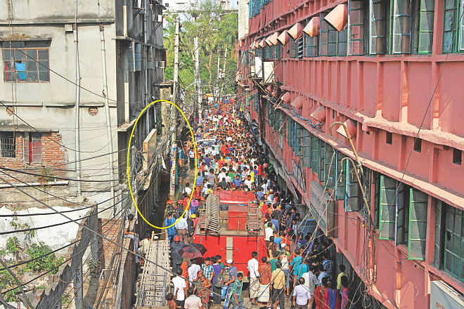 Onlookers and firemen in front of the shop, marked, in the narrow alley near Farmgate. The shop on the ground floor of a residential building sells accessories to garment factories nearby. The explosion of chemicals even injured a cook in a restaurant on the ground floor of the pink building that houses several apparel factories.  Photo: Palash Khan