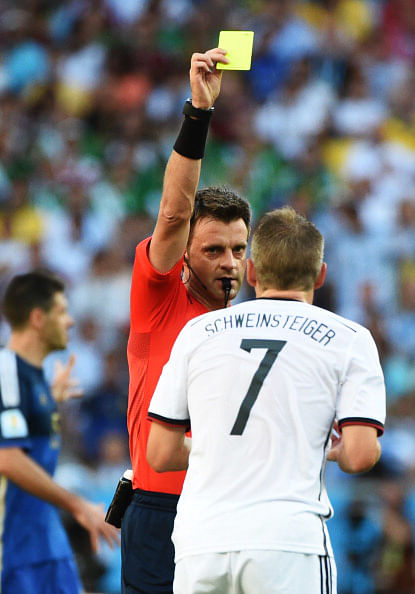 Italian referee Nicola Rizzoli (L) shows a yellow card to Germany's midfielder Bastian Schweinsteiger (R) during their 2014 FIFA World Cup final match at the Maracana Stadium in Rio de Janeiro on July 13, 2014. Photo: Getty Images