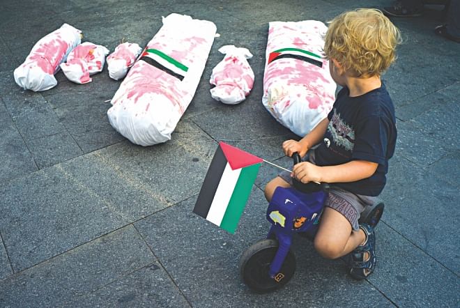 A boy holding the Palestinian flag rides on his plastic motorbike around mock-ups of dead Gaza residents during a rally in solidarity with Palestinians in Prague. Photo: AFP