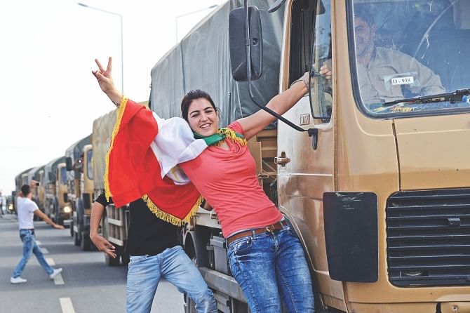 A Kurdish woman makes the victory sign as peshmerga convoys cross through the Habur border crossing along the Turkish-Iraqi border, yesterday.  Photo: AFP