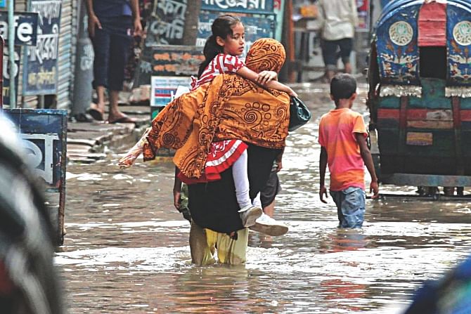 A mother picks up her school-going child in her arms to take her to school through knee-deep water on Ziaur Rahman Sarani in Matuail. Photo: Anisur Rahman