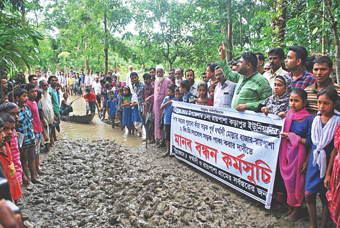 People of Raipasha-Karapur union in Barisal Sadar upazila formed a human chain at Dharmadi-Raipasha point of a two-kilometre-long muddy road on Sunday, demanding that the authorities concerned convert the road near the city into a metalled one. Photo: Star