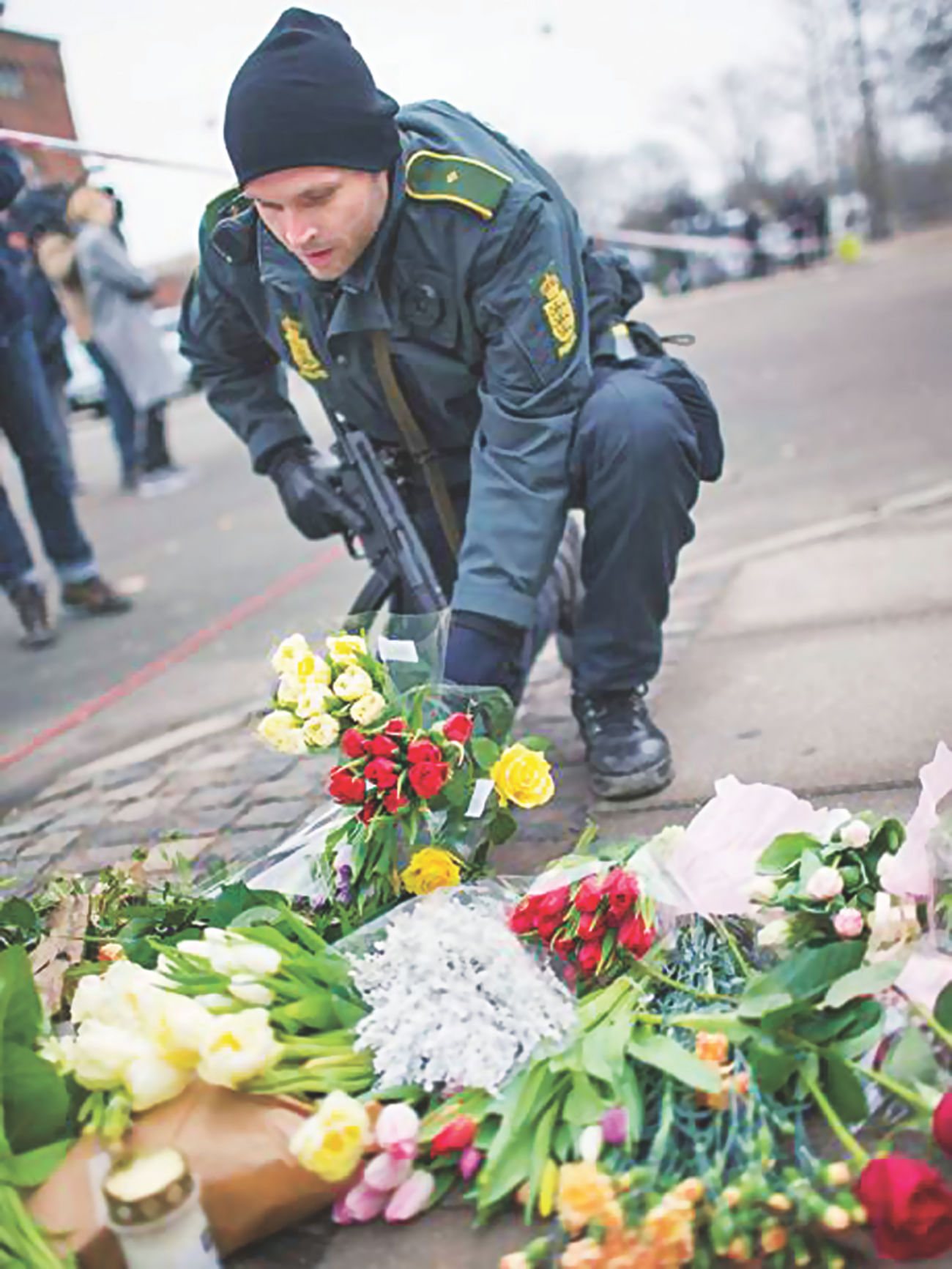 A policeman places flowers close to the scene of the cafe shooting in Oesterbroin. Photo: Independent.Co.UK 