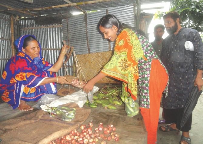 A woman selling daily commodities at her shop in the makeshift market at Kalikapur Island char village of Votmari union at Kaliganj upazila in Lalmonirhat. Photo: star