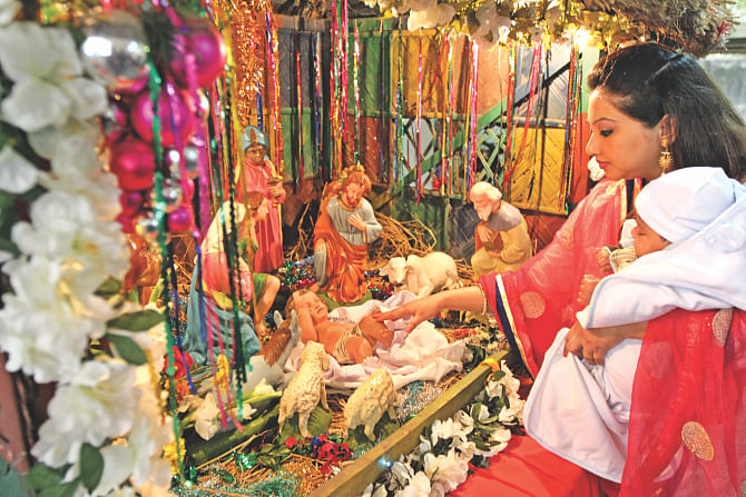A woman with her child touches the idol of the baby Jesus at Kakrail Church in the capital yesterday during a Christmas service. Photo: Sk Enamul Haq