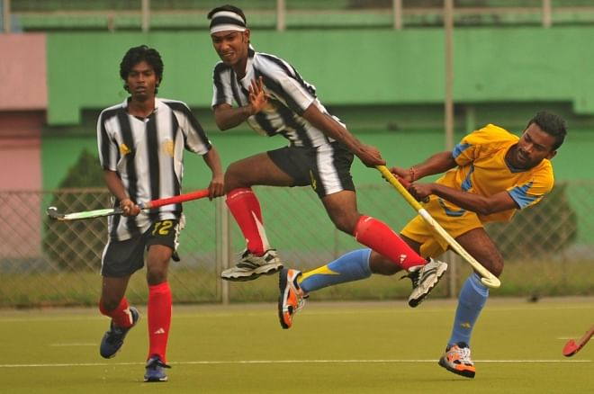 Abahani's Jubair Hasan Niloy (R), who is executing a reverse-hit to score his team's fourth goal, sends a Dhaka Wanderers defender (C) running for cover during the opening match of the UCB Club Cup hockey tournament at the Maulana Bhasani National Hockey Stadium on Tuesday. PHOTO: STAR