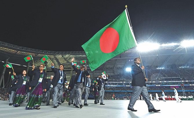Celebrated shooter Abdullah Hel Baki (R) bears the national flag as he leads the Bangladesh contingent during the opening ceremony of the 17th Asian Games at the Incheon Stadium yesterday. PHOTO: AFP