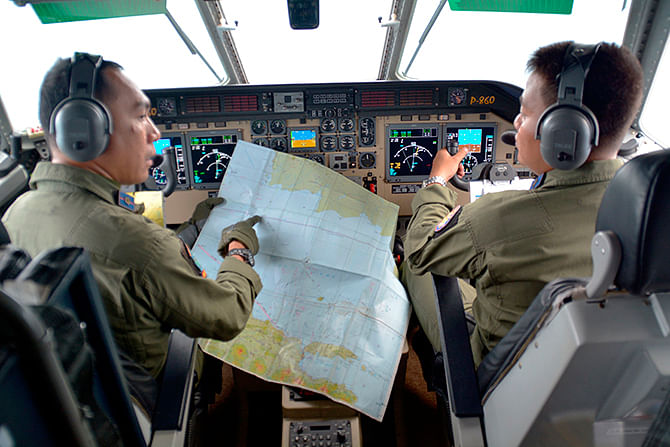 Pilot of Navy airplane CN235 M. Naim holds a map to co-pilot Rahmad while flying over the Java sea during joint search operations of AirAsia flight QZ8501 December 29, 2014 in this photo taken by Antara Photo. Photo: Reuters