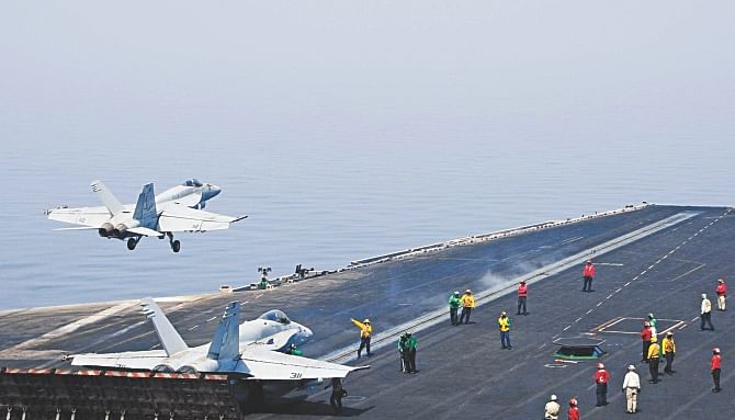 Sailors directing aircraft, as an F/A-18E Super Hornet takes off from the flight deck of the aircraft carrier USS George HW Bush on August 1, 2014 in the Gulf.  Photo: AFP, AP
