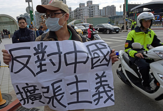 An anti-China protester displays a poster reading ‘oppose China expend out’ outside the venue of 2014 Cross-Strait CEO Summit in Taipei yesterday. Photo: AFP 