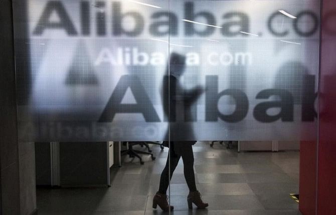 An employee is seen behind a glass wall with the logo of Alibaba at the company's headquarters on the outskirts of Hangzhou, Zhejiang province.  Photo: REUTERS/FILE 