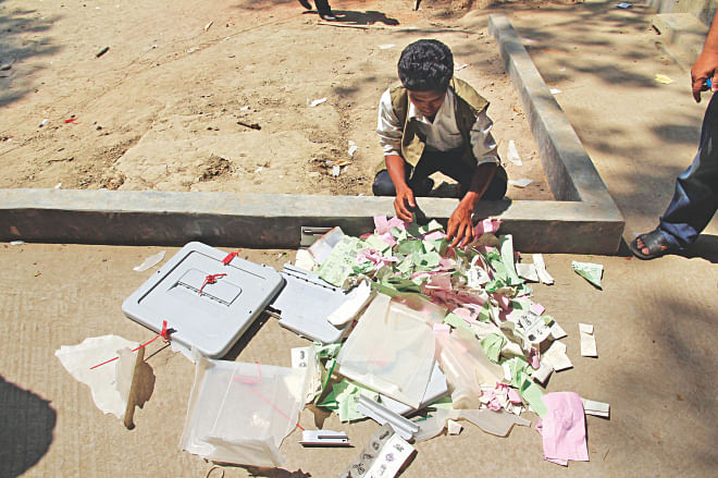A man rummages through ballot papers and box thrown out of a polling station in Comilla's Brahmanpara during an attack by AL supporters yesterday. Photo: Star
