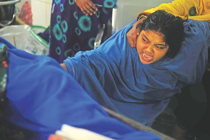 In shock, Champa Akhter won't let go of her husband Nur-e Alam's body at the burn unit of Dhaka Medical College Hospital yesterday. Nur was injured in a petrol bomb attack on a bus in Jatrabari on January 23.  Photo: Anisur Rahman
