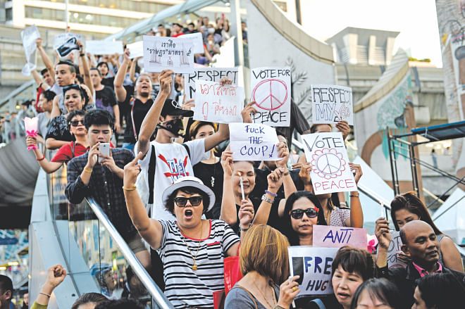 Anti-coup activists hold signs as they gather in a protest in downtown Bangkok yesterday. Thailand's new military junta summoned the kingdom's ousted government leaders yesterday and banned them from leaving the country, following a coup that has provoked an international outcry. Photo: AFP