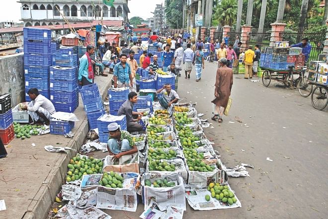 Fruit wholesalers sit in their makeshift shops on Badamtoli Road in Old Dhaka yesterday morning with hardly any buyers. Usually, the street is teeming with buyers in the mornings. Photo: Anisur Rahman