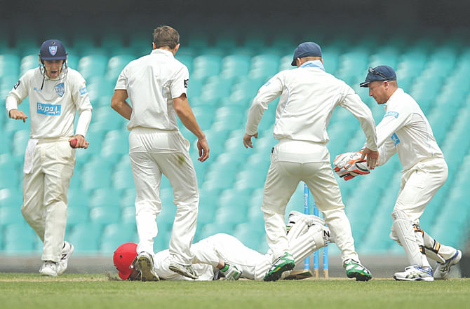 Australia batsman Phil Hughes falls to the ground after being struck by a Sean Abbott bouncer on the first day of the Sheffield Shield match between New South Wales and South Australia in Sydney yesterday. PHOTO: INTERNET