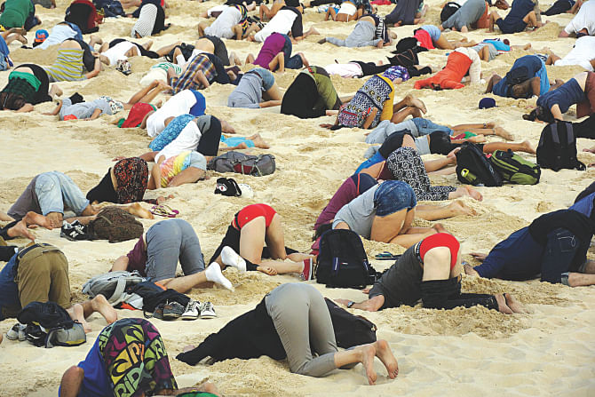 Australians yesterday bury their heads in the sands of iconic Bondi Beach to send a message to Prime Minister Tony Abbott about the dangers of climate change.  Photo: AFP