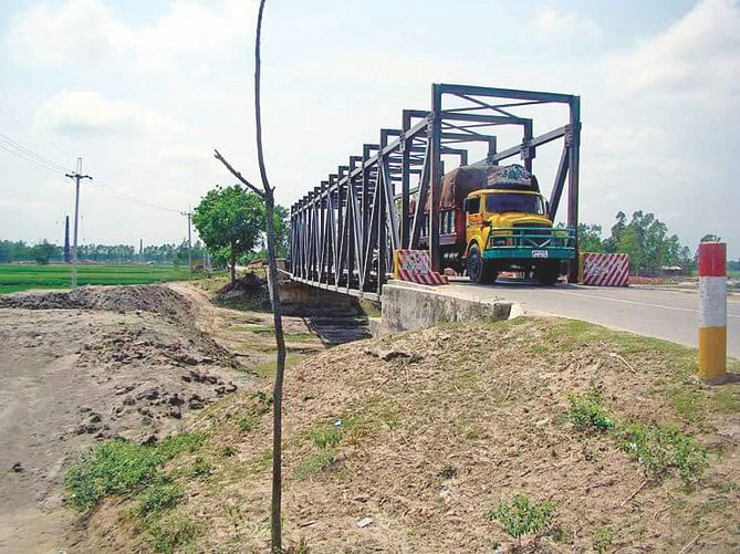 Passenger buses and goods-laden trucks using this dilapidated bailey bridge over Noleya canal on Gaibandha-Palshbari Road amid risk of accident. Though Ecnec is yet to approve the proposal for building a concrete bridge there, Roads and Highways Department has already started construction of a diversion road, spending Tk 38 lakh.  Photo: Star