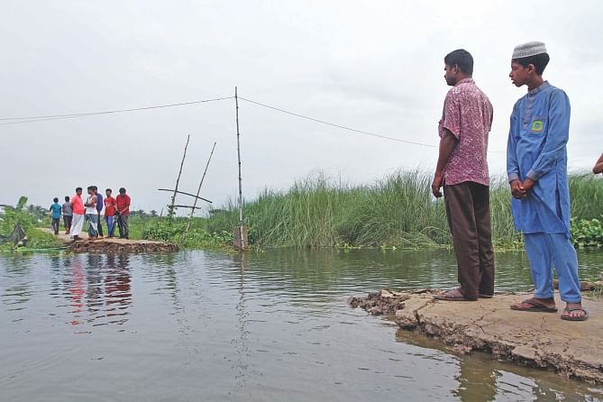 A 25-foot stretch of a road was swept away by water from the swelling Balu River in Kazir Jaiga village of the capital's Khilgaon Monday. With the road broken, over a hundred students from Nagdarpur and Nasirabad villages now have to make a 1.5km detour or use boats to go to Prof Ali Ahmad School and College in Kazir Jaiga. The sudden onrush has also adversely affected fish farming in a large swathe of the low-lying area. The photo was taken yesterday. Photo: Palash Khan
